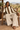 African female model seated on a safari lodge veranda in linen trousers