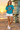 Female model wearing the tropical-blue tee near a lifeguard tower