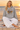 Female seated heather-grey hoodie look with white linen trousers