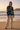 Full-length female model wearing the botanical all-over-print sweatshirt with wide-leg linen pants on a beach