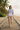 Full-length female model wearing the pastel all-over-print recycled hoodie on a tropical beach boardwalk