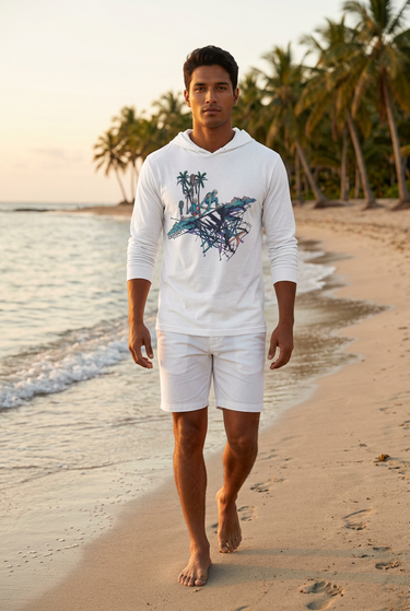 Male model walking the shoreline at golden hour in the white ODDSON hooded long-sleeve tee with white shorts