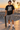 Male model wearing the black skull-skate tee beside a beachfront skate bowl
