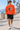Male model wearing the orange coffin skate sweatshirt on a beach boardwalk