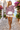 Pink hoodie with short ivory shorts in a coastal village
