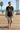 Black graphic tee styled with boardshorts on a beach boardwalk