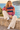 Blonde female model seated seaside in cream linen trousers