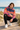 Brown-haired male model crouching on a beach boardwalk