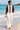Female barefoot beach look with cream linen trousers