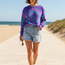 Female model styling the tie-dye sweatshirt with light-wash denim shorts