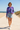 Female model styling the tie-dye sweatshirt with light-wash denim shorts