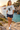 Female model wearing the ash skeleton skate tee beside a Mediterranean cove