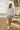 Female model wearing the floral sweatshirt with a pale-blue pleated skirt