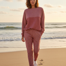 Female model wearing the matching Rose Mist sweatshirt and joggers on the beach