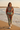 Female model wearing the matching terracotta and sage sweatshirt-and-jogger set on the beach