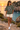 Female model wearing the military-green tee beside a Mediterranean cove