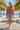 Female model wearing the Rose Mist sweatshirt with denim shorts