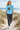 Female model wearing the sky-blue skeleton skate tee among coastal dunes