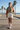 Female model wearing the terracotta spiral sweatshirt with cream boardshorts