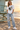 Female model wearing the white skeleton skate tee near a lifeguard tower