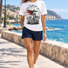 Female model wearing the white vampire skate tee on a sunny coastal promenade