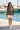 Female model wearing the Woodland Camo Hoodie with ivory shorts and white sneakers