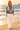 Floral sweater styled with ivory linen trousers on the beach