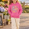 Four-year-old girl in raspberry hoodie at a coastal flower market