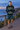 Geometric hoodie with teal boardshorts on a coastal boardwalk