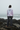 Full-length female model wearing the pastel all-over-print recycled hoodie on a misty Pacific shoreline