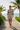 Full-length female model wearing the pastel striped all-over-print sweatshirt with tailored sand shorts on a beach boardwalk