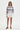 Full-length female model wearing the pastel striped all-over-print sweatshirt with white tailored shorts on a white background, front view