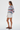 Full-length female model wearing the pastel striped all-over-print sweatshirt with white tailored shorts on a white background, side view
