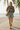 Full-length female model wearing the botanical all-over-print sweatshirt with vintage blue denim shorts on a beach boardwalk