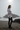 Full-length female model wearing the pastel striped all-over-print sweatshirt with black leggings on a Pacific shoreline