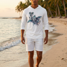 Male model walking the shoreline at golden hour in the white ODDSON hooded long-sleeve tee with white shorts
