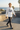 Male model walking through a coastal skatepark in the white ODDSON hooded long-sleeve tee with dark joggers