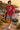 Male model wearing the cardinal-red tee beside a Mediterranean cove