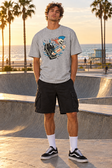 Male model wearing the sport-grey tee beside a beachfront skate bowl