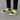 Man wearing yellow and black slip-ons with black jeans on pavement