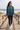 Ponytailed model wearing teal and gold hoodie on beach boardwalk