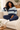 Relaxed seated model wearing the sweater and navy joggers in a cozy living room