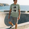 Sage ODDSON tee beside a seaside skate bowl