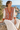 Seated look with orange geometric cardigan and white pleated skirt