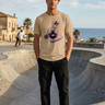 Tan ODDSON tee beside a coastal skate bowl