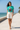Teal shirt with ivory shorts on a coastal promenade