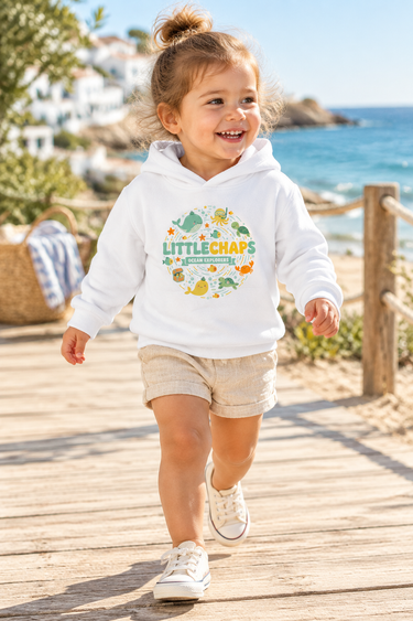Two-year-old girl in white hoodie on a beach boardwalk